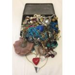 A tin of mixed costume jewellery to include necklaces.