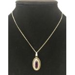 Oval amethyst set in a decorative pierced 9ct gold mount, on a 9ct gold chain.