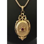 A 9ct gold locket set with a single ruby and bow decoration to top, on a snake chain.