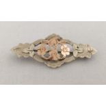 A silver sweetheart brooch with central rose gold flower and heart motif.