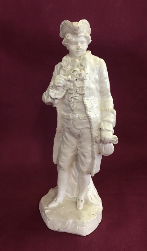 An 18th century Naples figurine of a gentleman holding a bag.