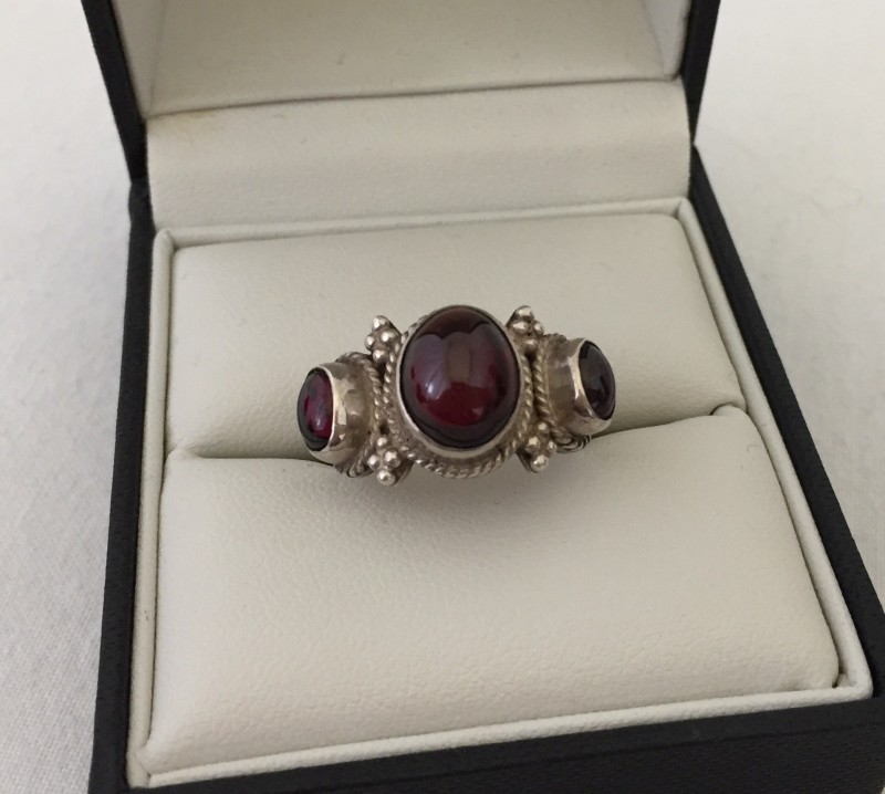 Ladies silver dress ring set with 3 oval garnet cabochons.