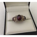 Ladies silver dress ring set with 3 oval garnet cabochons.