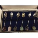 A boxed set of white metal teaspoons set with natural stones.