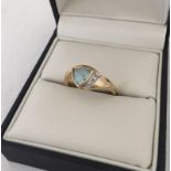 A 9ct gold dress ring set with triangular shaped blue topaz and 2 small diamonds.