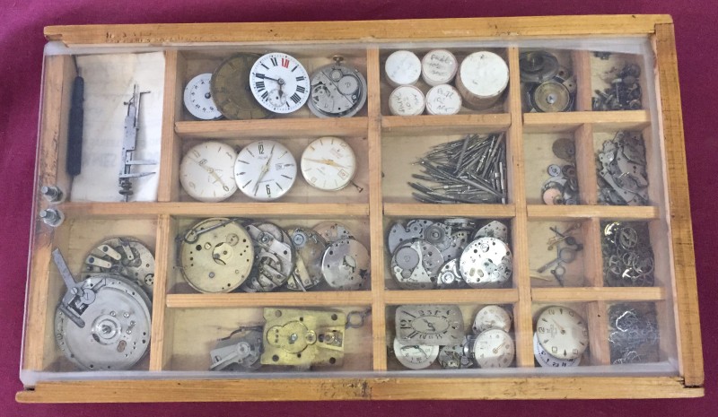 A box of watch parts to include faces, movements & watch makers measure.