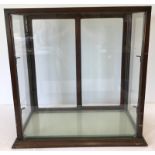 A dark oak framed table top glass display cabinet with 2 glass internal shelves.