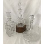 3 cut glass decanters. A spherical bottomed decanter in wooden stand together with 2 others.