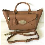 An unused brown leather handbag with detachable shoulder strap and dust cover.