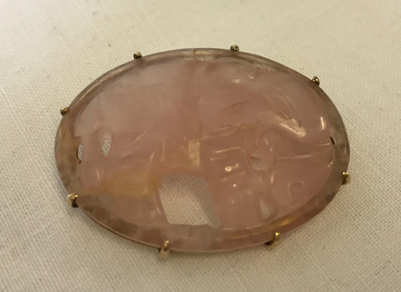 A carved rose quartz brooch with elephant design.