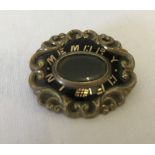 A vintage decorative mourning brooch with central glass panel.