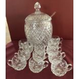 A large cut glass lidded punch bowl with 12 matching punch cups.