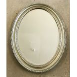 A large oval shaped oak framed bevel edged hall mirror. Painted silver.