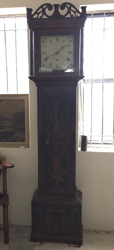 A dark oak long cased clock with carved detail to front.