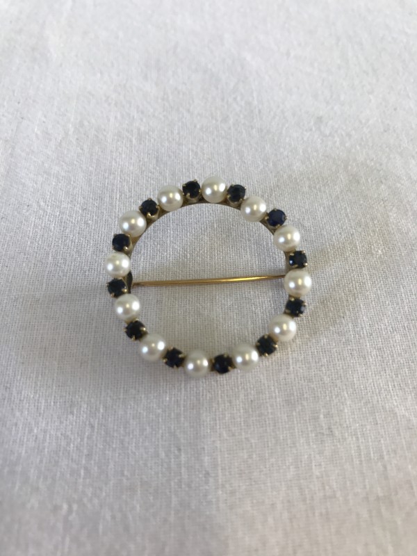 A vintage circular 14ct gold brooch set with pearls and blue stones.