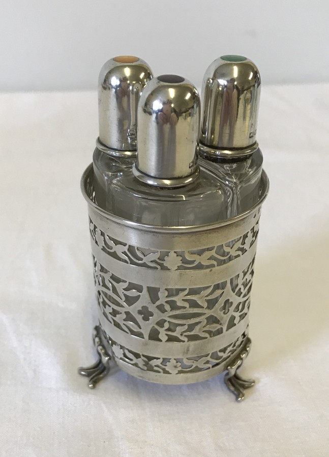 A 3 footed decorative circular silver scent bottle holder with 3 bottles.
