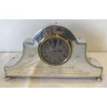 A silver cased mantle clock with engraving and bun feet.