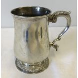 A heavy Georgian silver tankard with shaped handle and base.