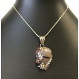 Polished agate pendant in a silver mount with silver overlay set with semi-precious stones.