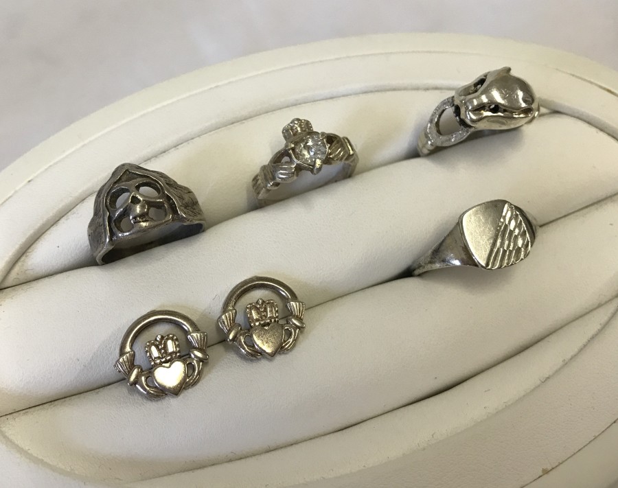 A collection of 4 silver rings of different designs and sizes.