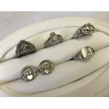 A collection of 4 silver rings of different designs and sizes.
