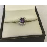 Pretty 9ct gold dress ring set with a central amethyst surrounded by clear stones.