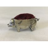 A hallmarked silver pig shaped pin cushion with red velvet cushion.