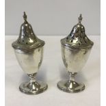 A pair of silver pounce pots on oval pedestal base with finial tops.