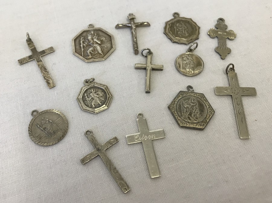 A collection of 7 silver cross pendants and 6 silver St Christopher's medals.