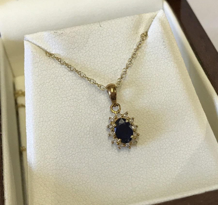 9ct gold pendant set with central blue sapphire encircled by white sapphires.