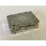 A decorative silver snuff box / stamp box with circular blank cartouche.