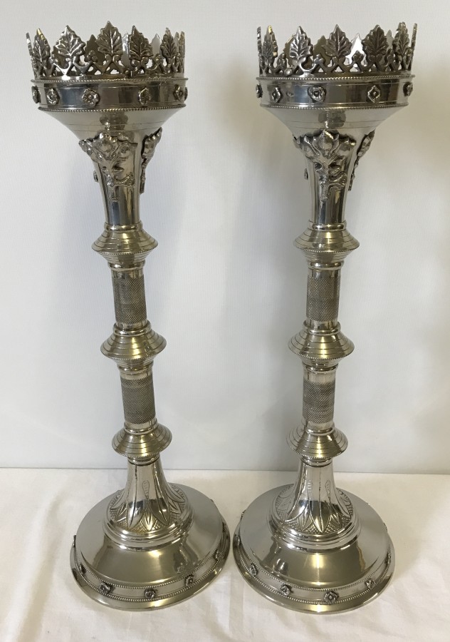 A large pair of silver coloured candlesticks with engraved detail and leaf design border to top rim.