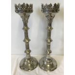A large pair of silver coloured candlesticks with engraved detail and leaf design border to top rim.