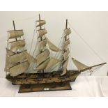 A wooden model of a 3 masted frigate ship on stand.