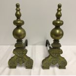 A pair of brass fire dogs with engraved detail to bottom.