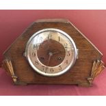 An Art Deco dark wood mantel clock with fan decoration to front.