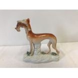 A Staffordshire ceramic figurine of a greyhound holding a rabbit.