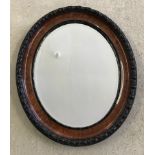 An oval carved wood frame bevelled edged wall mirror.