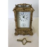 An ornate repeating carriage clock with enamel face and bevel edge glass panels.