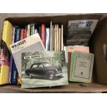 A box of vintage and modern car manuals and catalogues.