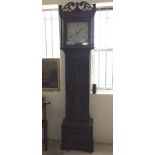 A dark oak long cased clock with carved detail to front.