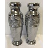 A pair of white metal vases.