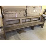 A vintage pine church pew with prayer book shelf to back.