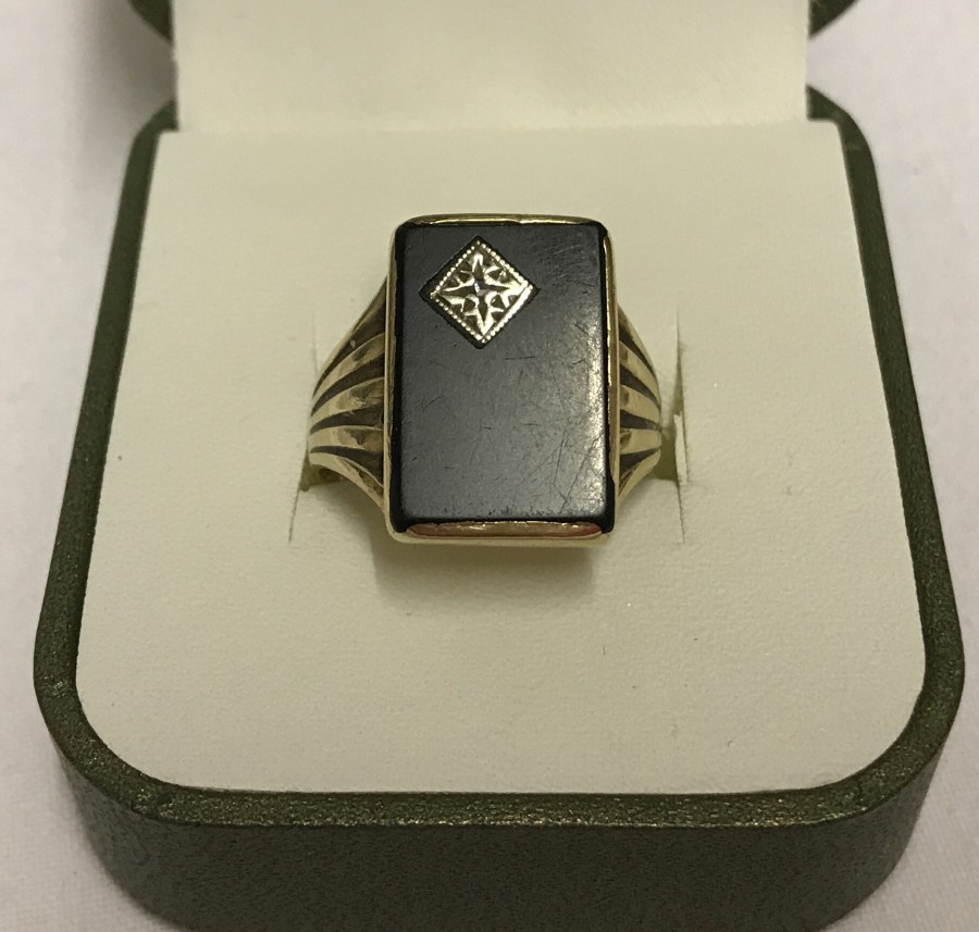 A 9ct gold gents ring with rectangular black onyx panel set with diamond chip.