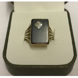 A 9ct gold gents ring with rectangular black onyx panel set with diamond chip.