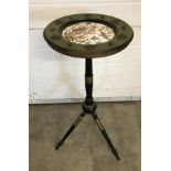 A black and gilt ceramic topped plant stand with tripod legs.