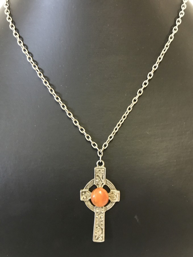 A pewter Celtic cross pendant set with orange stone.