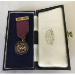 A boxed 9ct gold enamelled Fattorini & sons medal and pin on a maroon ribbon.