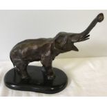 A cold painted hollow bronze figurine of an elephant mounted onto a wooden plinth.