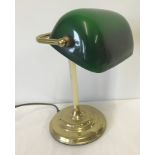 A brass based bankers style desk lamp with green glass adjustable shade.